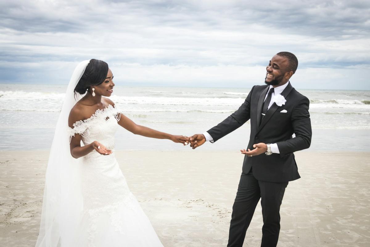 Une mariée et un marié se tiennent la main au bord de la mer